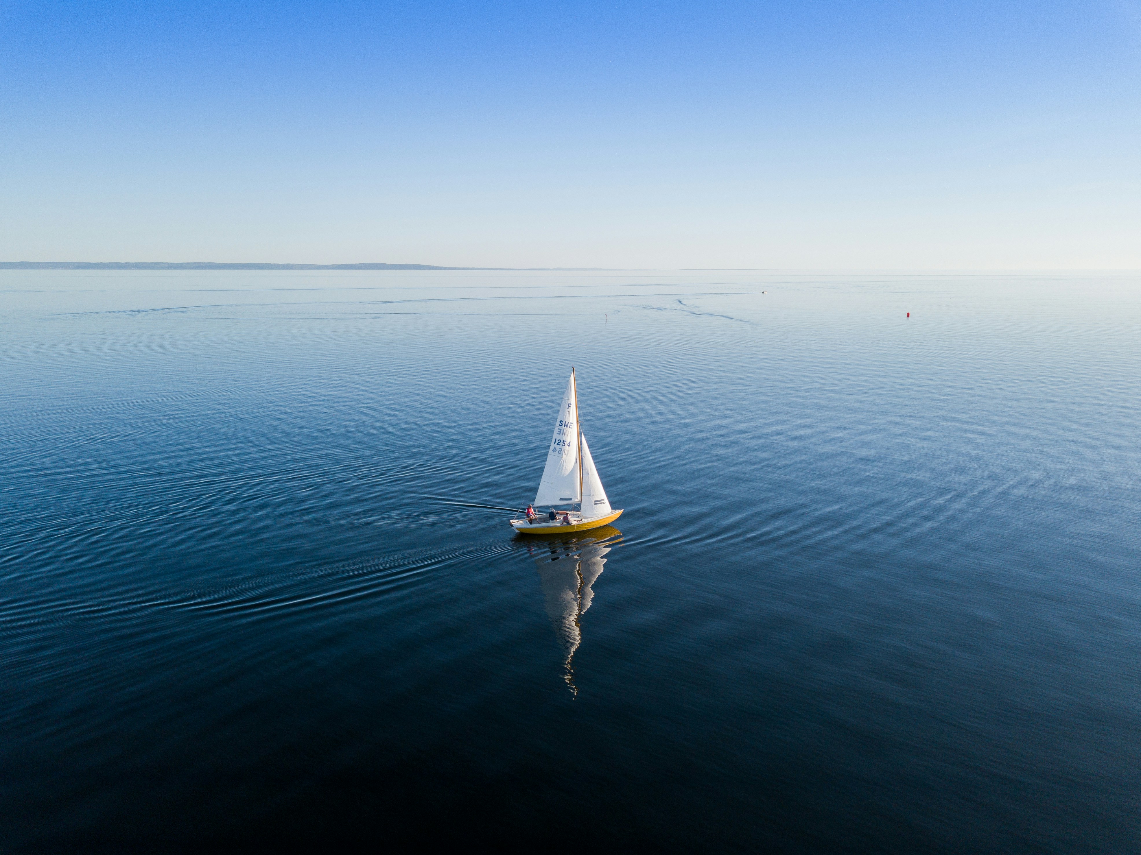 A lone sailboat crossing calm open water off the Mallorcan coast
